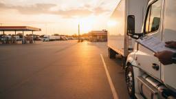 Semi truck with dry van trailer parked at a truck stop during golden hour