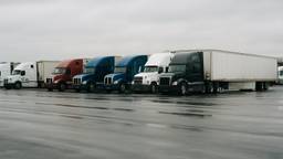Line of parked semi trucks at a quiet truck stop while FMCSA holds off on USDOT deactivations