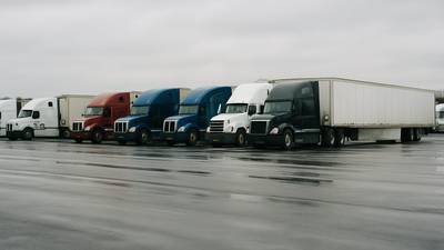 Line of parked semi trucks at a quiet truck stop while FMCSA holds off on USDOT deactivations
